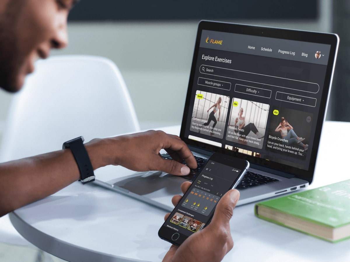 Mockup showing smiling person at their laptop with a phone in their hand. The laptop shows the explore exercise screen while the phone shows the progress log.